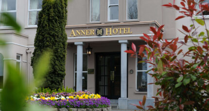 Entrance of The Anner Hotel with vibrant flowers and lush greenery.