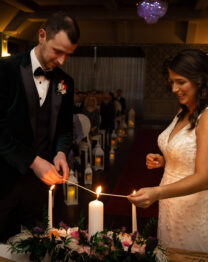 Bride and groom lighting unity candle at elegant wedding ceremony in Anner Hotel.