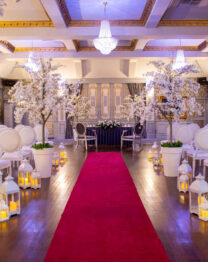 Elegant event hall with flower decor and red carpet, set for a ceremony at The Anner Hotel.