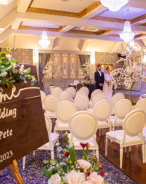 Elegant wedding setup with floral decorations and guests at a hotel venue.