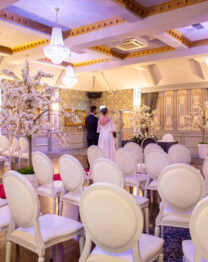 A couple standing in an elegant hotel ballroom adorned with floral decorations.
