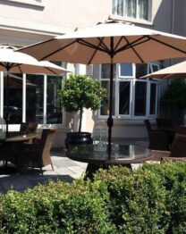 Charming outdoor seating area at The Anner Hotel with large umbrellas and wicker chairs.