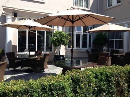 Charming outdoor seating area at The Anner Hotel with large umbrellas and wicker chairs.