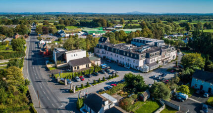 Aerial view of The Anner Hotel and surrounding greenery on a sunny day.