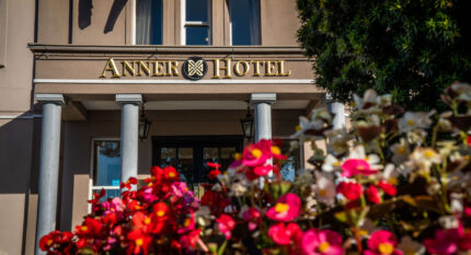 Entrance of The Anner Hotel with blooming flowers in the foreground.
