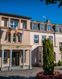 Elegant hotel facade with flags, surrounded by greenery, welcoming for families and couples.