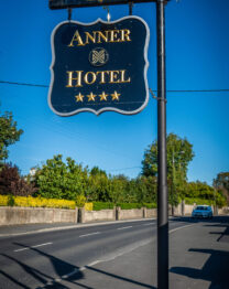 Exterior sign for The Anner Hotel, showcasing four-star rating, with blue sky backdrop.