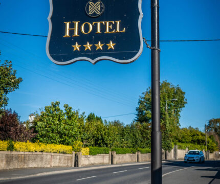 Exterior sign for The Anner Hotel, showcasing four-star rating, with blue sky backdrop.