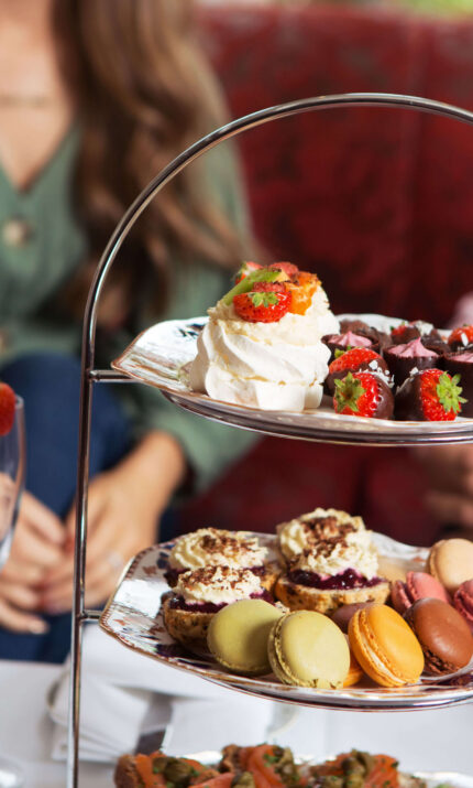 Family enjoying afternoon tea with sweet treats at a cosy hotel setting.