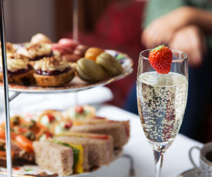 Family enjoying afternoon tea with champagne and treats at a cosy hotel lounge.