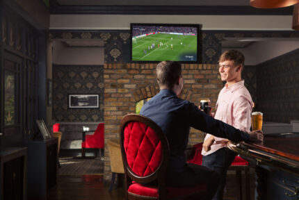 Two friends enjoying drinks at The Anner Hotel bar watching a football match.