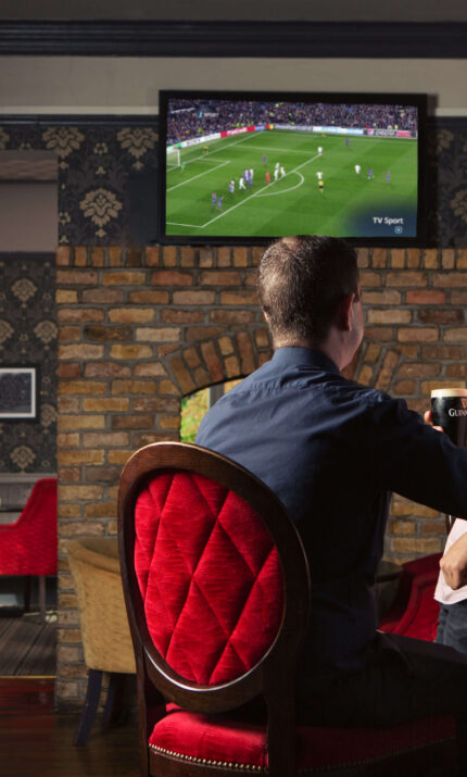 Two friends enjoying drinks at The Anner Hotel bar watching a football match.