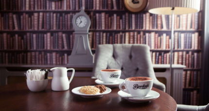 Cosy lounge with hot drinks and biscuits, featuring an elegant library-themed decor.