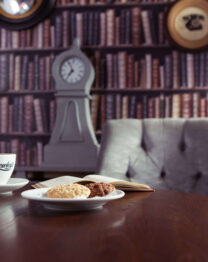 Cosy hotel lounge with coffee, biscuits, and book, inviting relaxation.