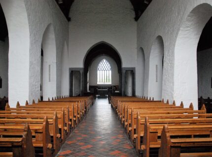 Elegant church interior with wooden pews and arched windows.