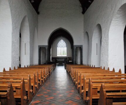 Elegant church interior with wooden pews and arched windows.