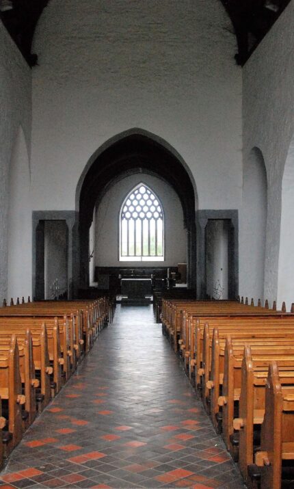 Elegant church interior with wooden pews and arched windows.