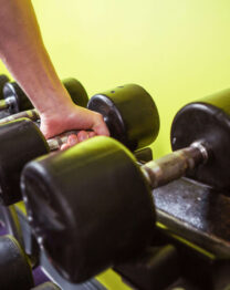 A person lifts a dumbbell in a bright gym at The Anner Hotel.