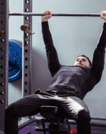 A guest exercises on gym equipment in a modern fitness centre with colourful weight plates.