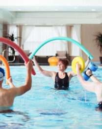 Group enjoying aqua aerobic class in indoor pool at The Anner Hotel, surrounded by bright decor.