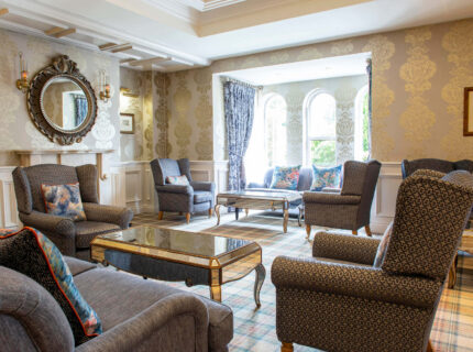 Elegant hotel lounge with cosy armchairs and large windows inviting relaxation.