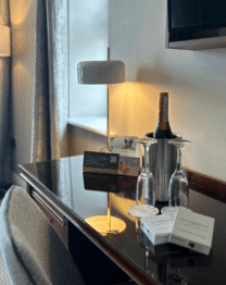 Elegant hotel room with wine and glasses on the table, inviting atmosphere for relaxation.