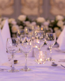 Elegant table setting with white linens and glassware in a warm, inviting atmosphere.