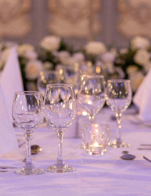 Elegant table setting with white linens and glassware in a warm, inviting atmosphere.