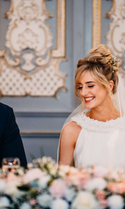 A joyful couple at a wedding reception in a beautifully decorated ballroom at The Anner Hotel.