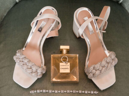 Elegant high heels and perfume on an upholstered chair in a luxurious hotel room.