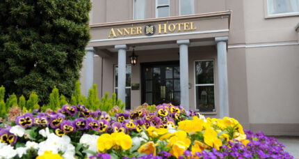 Vibrant flowers in front of The Anner Hotel entrance, inviting and elegant setting.