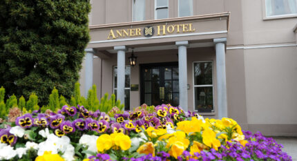 Vibrant flowers in front of The Anner Hotel entrance, inviting and elegant setting.