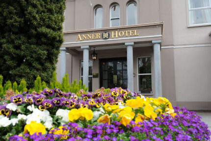 Vibrant flowers in front of The Anner Hotel entrance, inviting and elegant setting.