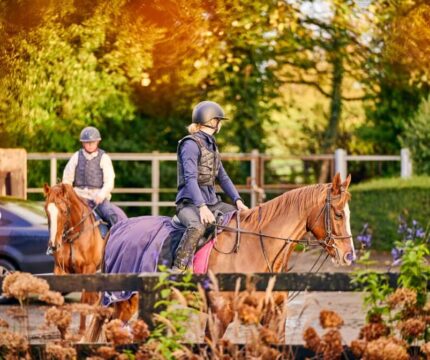 A couple riding horses in a scenic, autumnal setting near The Anner Hotel.