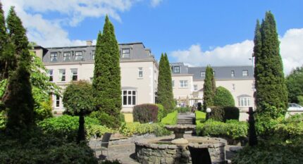 Elegant hotel garden with fountain and towering trees, perfect for family gatherings.