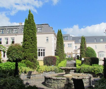 Elegant hotel garden with fountain and towering trees, perfect for family gatherings.