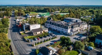 Aerial view of The Anner Hotel, surrounded by greenery, with people enjoying leisure activities outside.