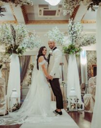 A couple stands joyfully in a beautifully decorated wedding venue at The Anner Hotel.