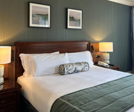 Elegant hotel room with a plush double bed, soft lighting, and charming decor.