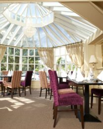 Elegant dining area with striped chairs under a glass ceiling at The Anner Hotel.