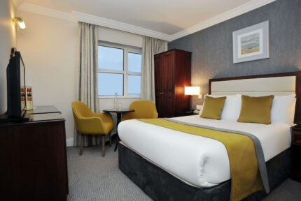 Cosy hotel room with a large bed, mustard chairs, and a view. Ideal for family stays.