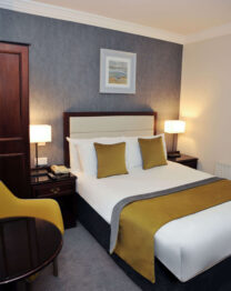 Elegant hotel room with cosy double bed and warm lighting, perfect for relaxation.