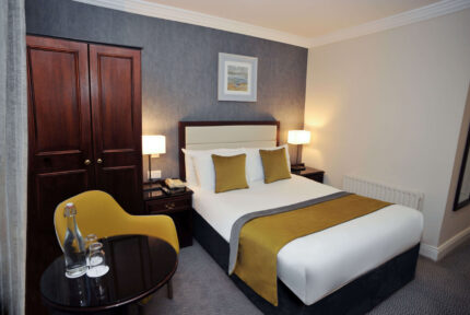Elegant hotel room with cosy double bed and warm lighting, perfect for relaxation.