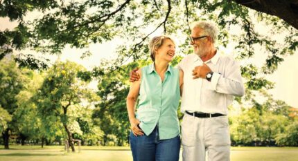 A joyful couple strolls arm-in-arm in a sunny, lush garden at The Anner Hotel.