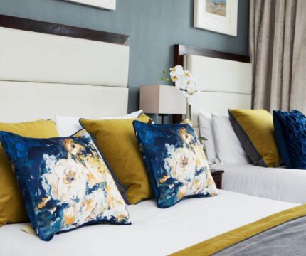 Elegant hotel room with plush bedding and decorative pillows, inviting and cosy ambiance.