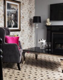 Elegant hotel room with plush chairs, a cosy fireplace, and floral decor at The Anner Hotel.