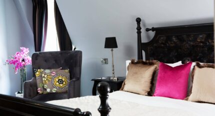 Elegant hotel room with plush pillows and bright pink accents.
