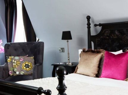 Luxurious hotel room with a plush bed, vibrant cushions, and elegant decor.