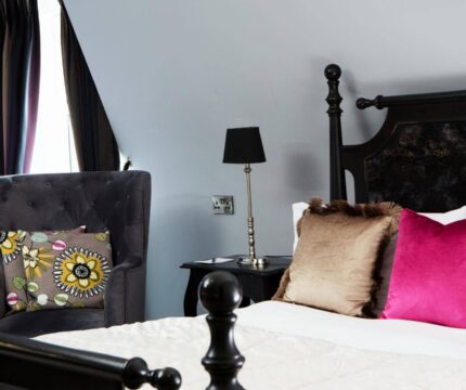 Luxurious hotel room with a plush bed, vibrant cushions, and elegant decor.