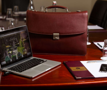 Luxurious conference setup with laptop, briefcase, and stationery at a hotel.